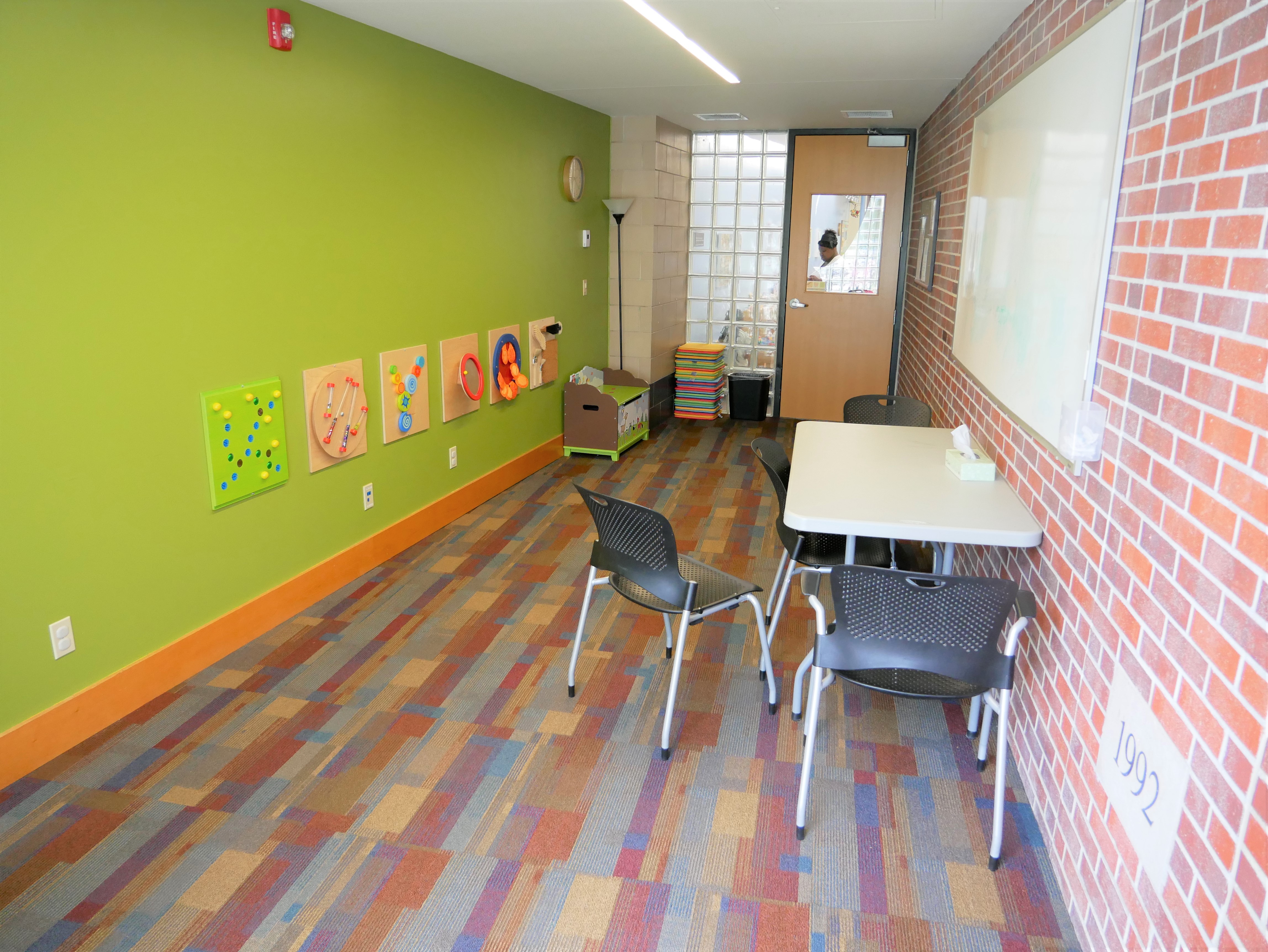 Forest Avenue Study Room with lime green wall, brick wall, and a rectangular table with chairs and a mounted whiteboard