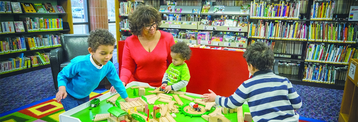 Woman sitting with three young children in the children's area of the library