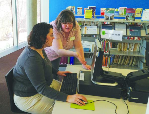Photo of library staff on a computer. 